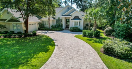 Curved brick paver driveway with lush landscaping